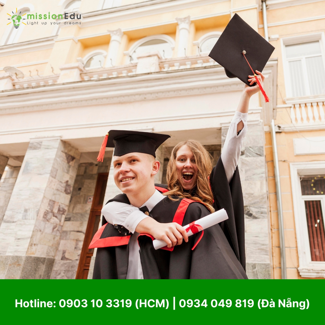 Một cặp sinh viên đại học đang ăn mừng lễ tốt nghiệp một cách đầy phấn khích. Nam sinh mặc áo cử nhân đang bế bạn nữ lên, trong khi cả hai cùng giơ mũ và bằng tốt nghiệp lên cao. Cả hai đều mỉm cười rạng rỡ, thể hiện niềm vui và sự tự hào.